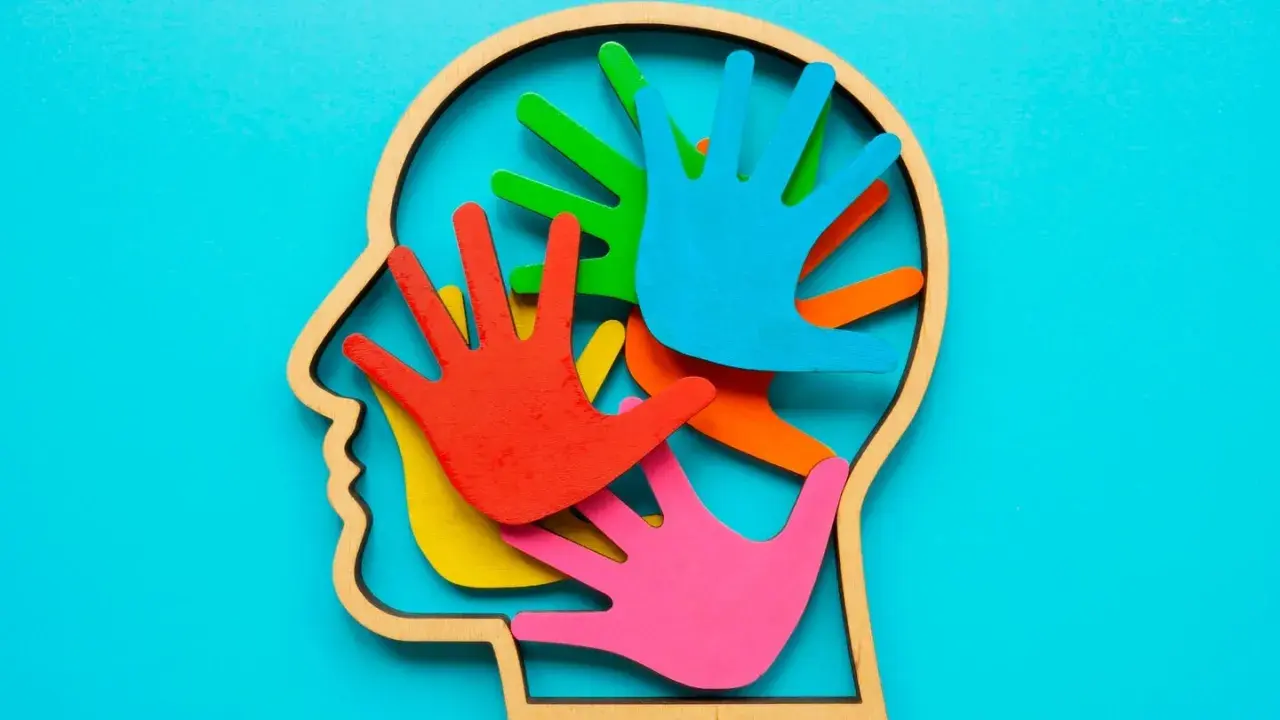 Bunte Hände im Kopfprofil symbolisieren die Vielfalt der Wahrnehmung. Wer stellt Autismus fest? Fachleute mit Verständnis für diese neurologische Besonderheit.