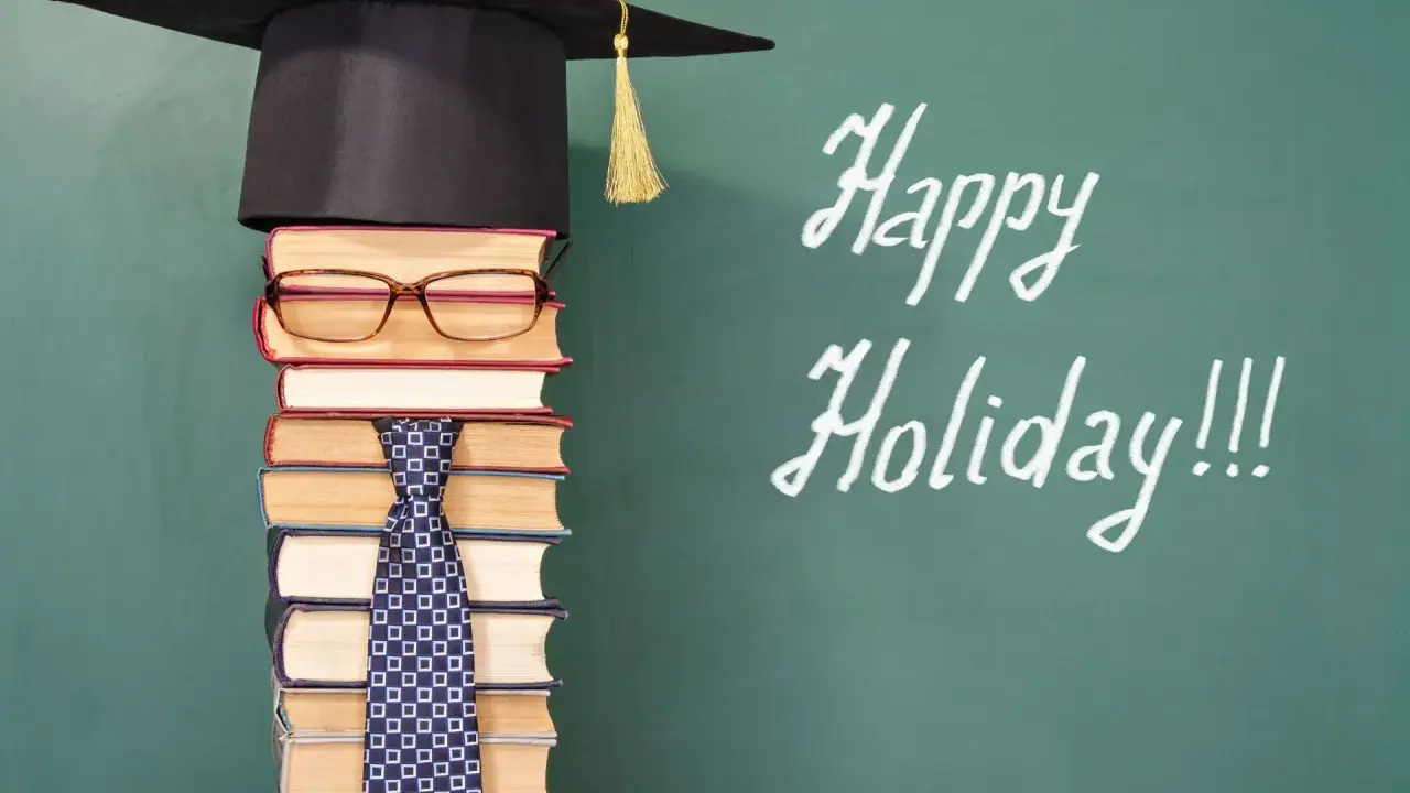 Ein Stapel Bücher mit Hut und Krawatte, der an die letzte Schulwoche erinnert. "Happy Holiday!!!" steht auf der Tafel.