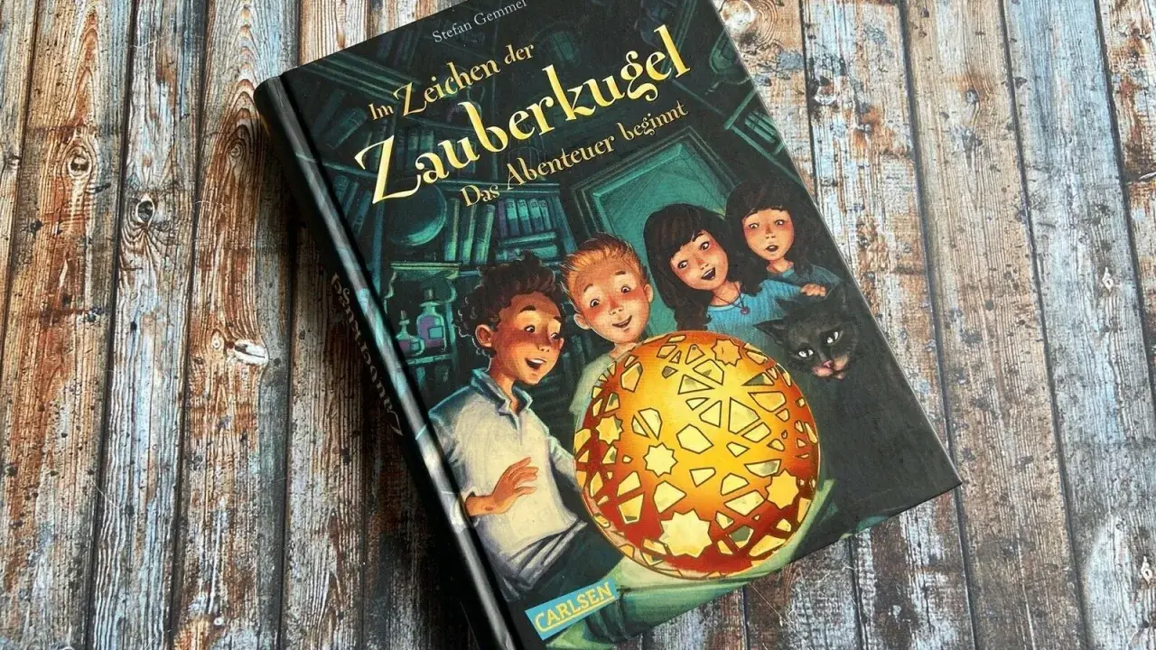 Ein Buchcover mit dem Titel "Im Zeichen der Zauberkugel". Kinder und eine Katze blicken neugierig auf eine leuchtende Kugel.