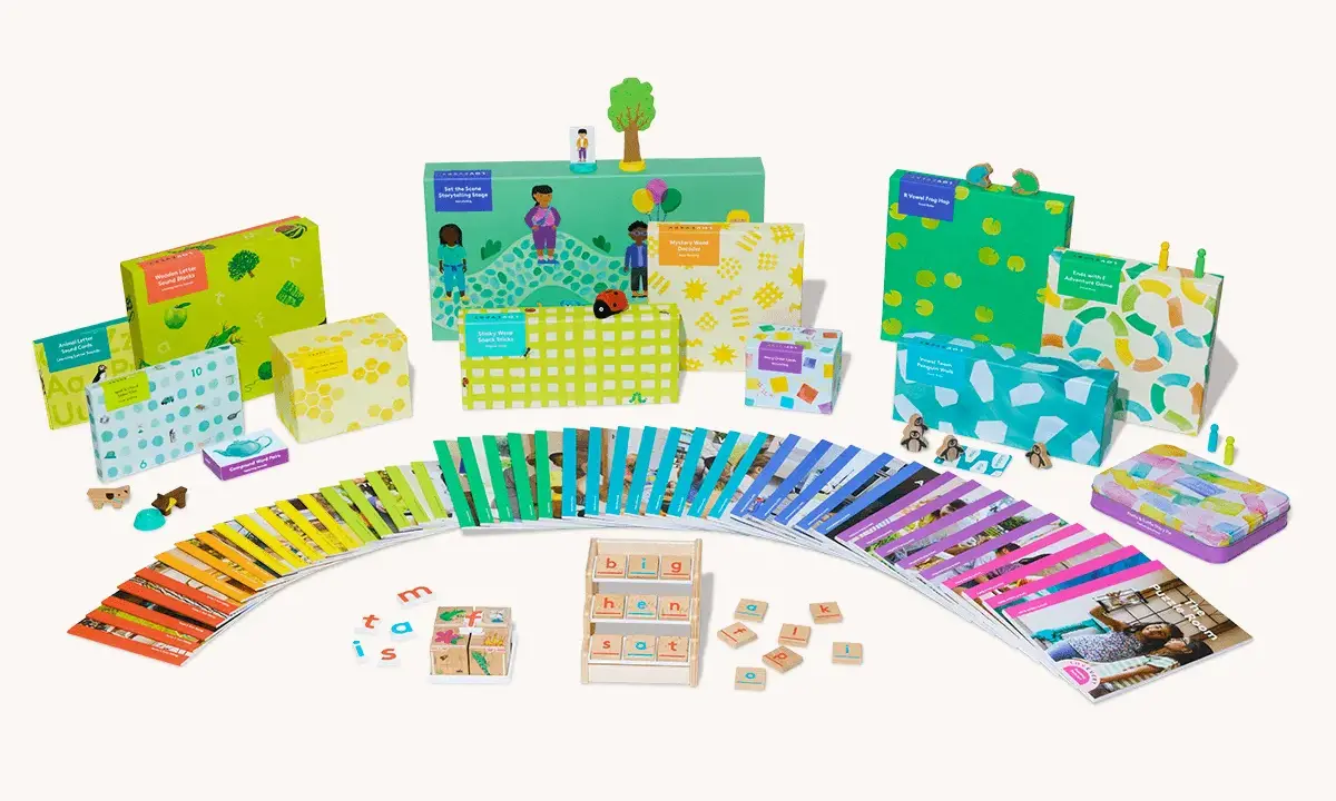 Bunte Lernspiele und Karten fördern spielerisch lesen lernen. Kleine Holzfiguren und bunte Boxen laden zum Entdecken ein.