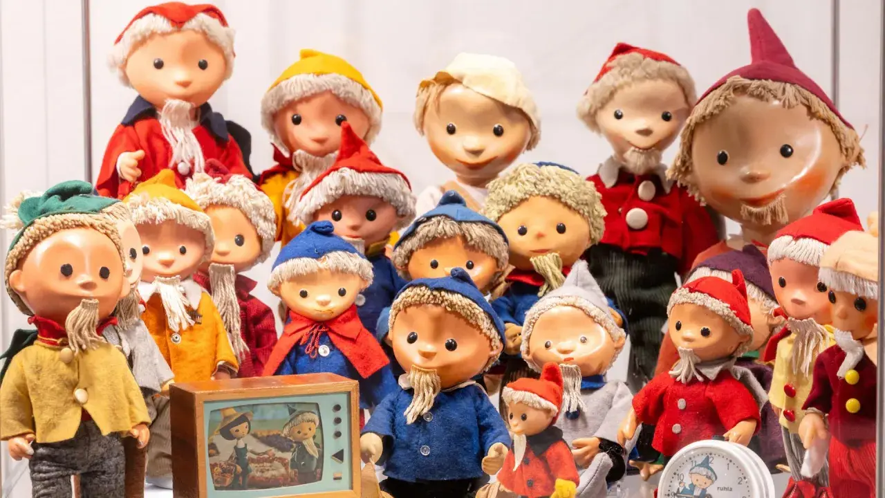 Eine Sammlung von Sandmann-Charakteren in bunten Kostümen, einige mit Bart und Mützen, stehen dicht gedrängt.