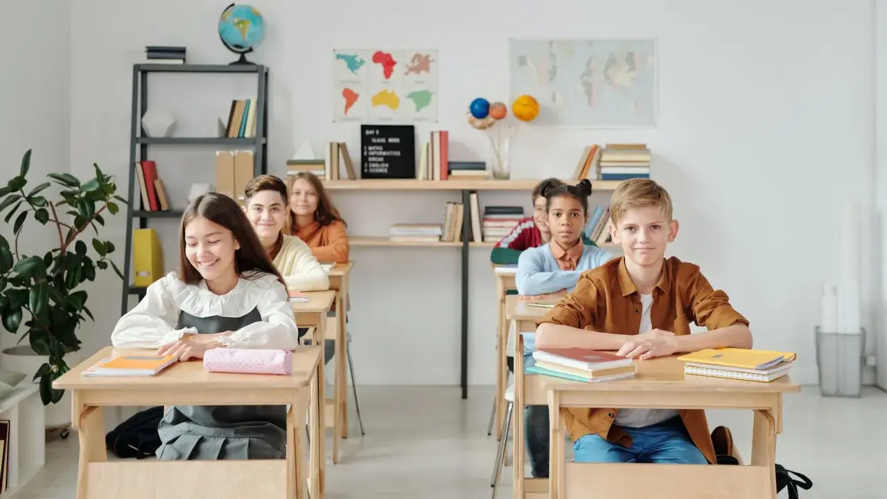 Schüler sitzen an Holztischen. Eine Lehrerin könnte hier kreative Sitzordnung Grundschule Ideen umsetzen.