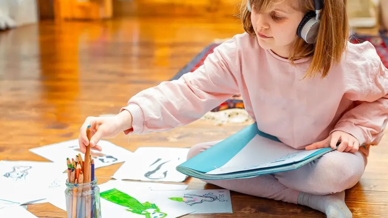 Mädchen mit Kopfhörern wählt Buntstift für Zeichnung. Kreativer Umgang mit Asperger-Kindern durch Kunst.
