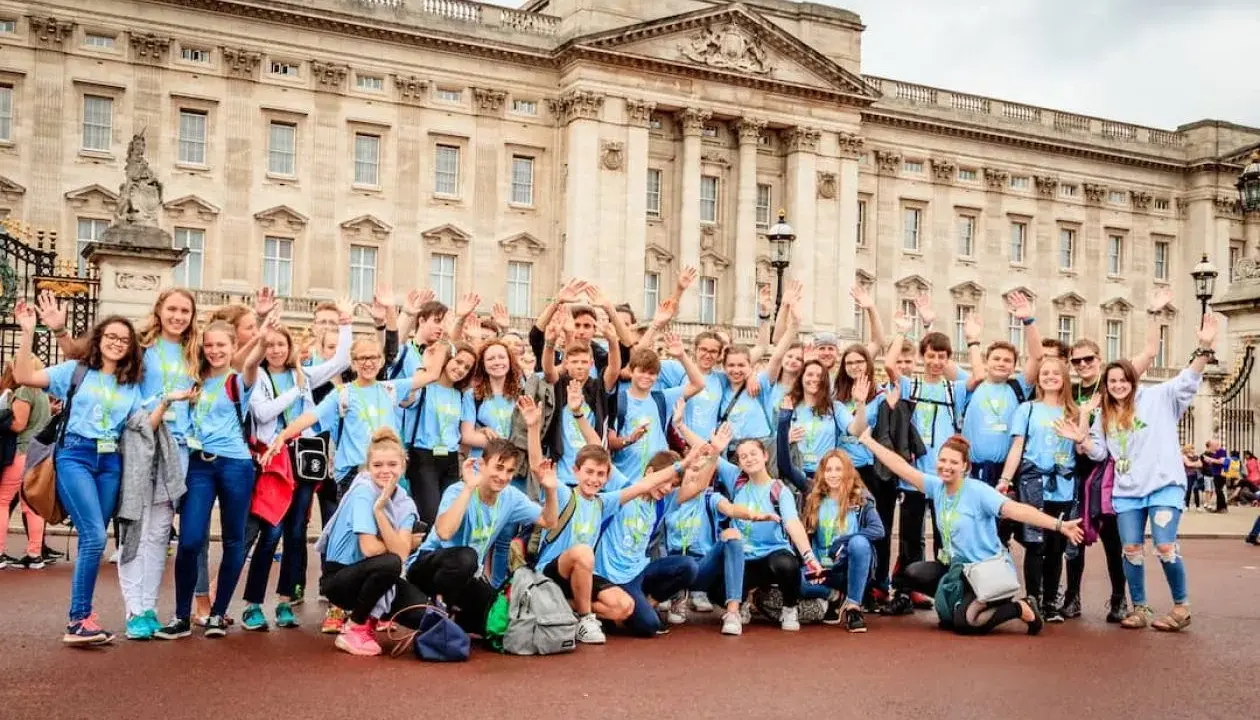 Eine fröhliche Gruppe Jugendlicher vor dem Buckingham Palace, bereit für ihr sprachcamp englisch.