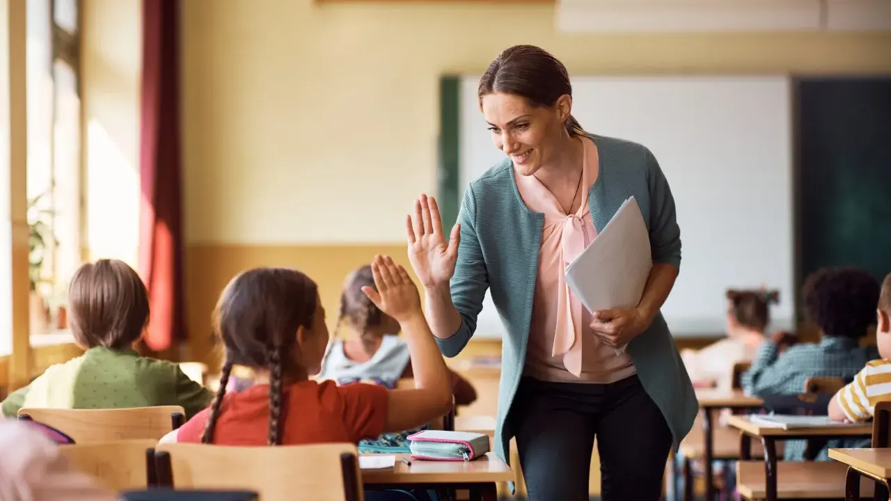 Lehrerin gibt einem Grundschüler einen High-Five. So kann man Kinder zum Lernen motivieren.