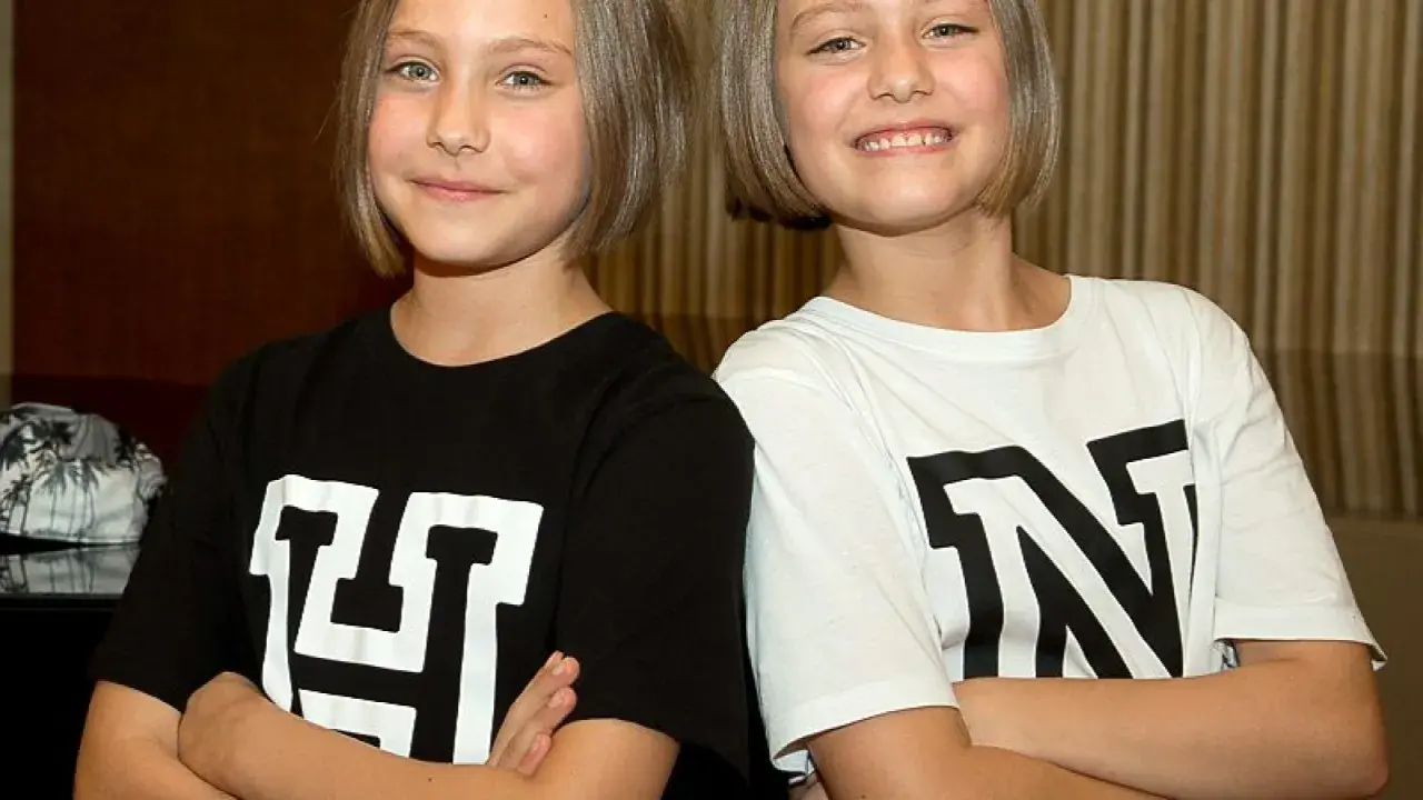 Zwei Mädchen mit kurzen Haaren, die T-Shirts mit den Buchstaben "H" und "N" tragen. Man fragt sich, wie alt sind Hanni und Nanni wohl?