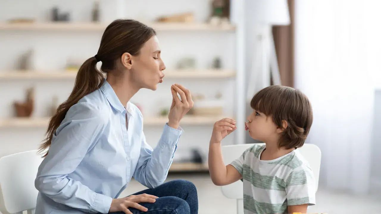 Eine Frau und ein Kind machen Lippenbewegungen. Dies kann ein Hinweis sein, um autismus erkennen kind.