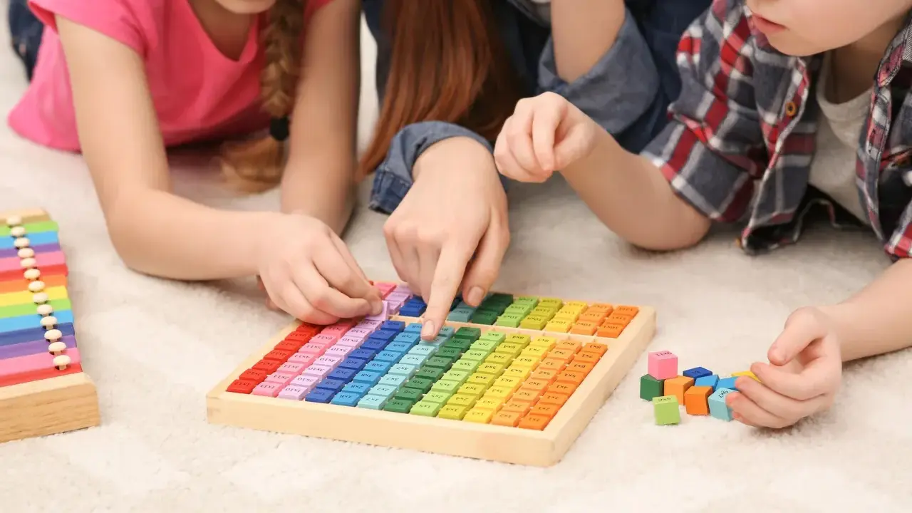Kinder lernen spielerisch Mathe mit bunten Holzbausteinen und einem kleinen Abakus.