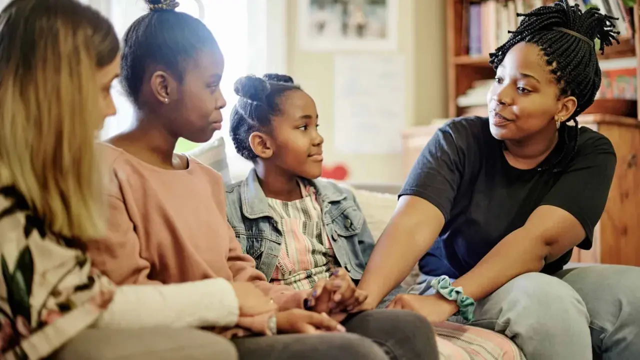 Eine Familie spricht auf dem Sofa. Das jüngste Kind, das oft als hyperaktives Kind beschrieben wird, hört aufmerksam zu.