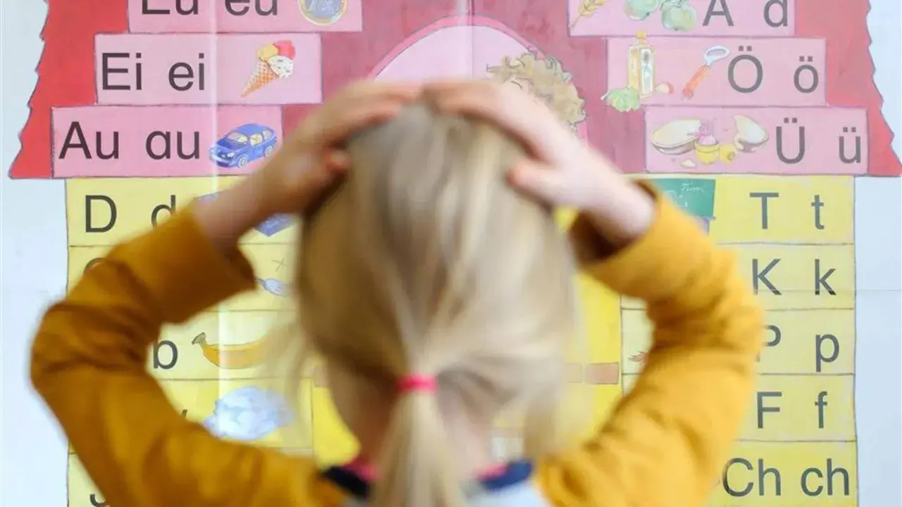Ein Kind mit Händen am Kopf vor einer Buchstabenwand, die auf Schwierigkeiten beim Lesen und Schreiben (LRS) bei Kindern hindeuten könnte.