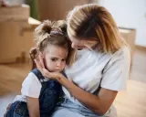Mutter tröstet ihr Kind, das Angst vor anderen Kindern hat.
