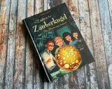 Ein Buchcover mit dem Titel "Im Zeichen der Zauberkugel". Kinder und eine Katze blicken neugierig auf eine leuchtende Kugel.
