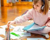 Mädchen mit Kopfhörern wählt Buntstift für Zeichnung. Kreativer Umgang mit Asperger-Kindern durch Kunst.
