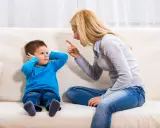 Mutter schimpft mit Sohn, der sich die Ohren zuhält. Ein typischer Streit mit Eltern, der die Geduld auf die Probe stellt.