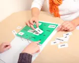 Therapeuten üben mit Karten, um die Ursachen von Lernbehinderungen zu verstehen. Wörter wie "HAT", "TRAURIG" und "HAAR" werden sortiert.
