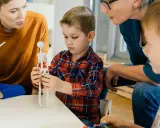Kinder lernen mit einem Skelettmodell und einem Windrad. Die Lehrerin erklärt geduldig, wie wichtig es ist, sich auf Details zu konzentrieren, auch bei ads adhs.