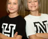 Zwei Mädchen mit kurzen Haaren, die T-Shirts mit den Buchstaben "H" und "N" tragen. Man fragt sich, wie alt sind Hanni und Nanni wohl?