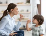 Eine Frau und ein Kind machen Lippenbewegungen. Dies kann ein Hinweis sein, um autismus erkennen kind.