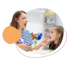 Logopädin zeigt einem Mädchen, wie man Laute richtig formt. So lernen Kinder am besten neue Sprechfähigkeiten.