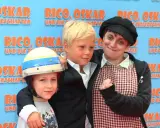 Drei Personen vor einem blauen Banner mit der Aufschrift "Rico, Oskar und die Tieferschatten". Ein Junge mit Helm, ein anderer Junge im Anzug und eine Frau mit Schal.
