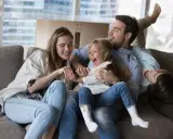 Eine Familie lacht und spielt auf dem Sofa. Das gemeinsame Lachen ist ein schönes Ritual.