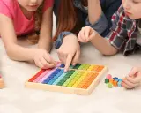 Kinder lernen spielerisch Mathe mit bunten Holzbausteinen und einem kleinen Abakus.