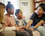 Eine Familie spricht auf dem Sofa. Das jüngste Kind, das oft als hyperaktives Kind beschrieben wird, hört aufmerksam zu.