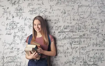 Ein lächelndes Mädchen mit Büchern vor einer Wand voller mathematischer Formeln. Sie zeigt, wie kann man sich in Mathe verbessern: durch Lernen und Üben.