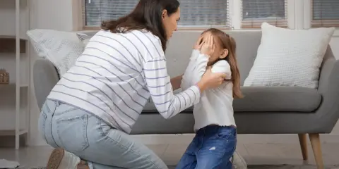 Frau tröstet weinendes Kind, das sich die Augen zuhält. Ein Gespräch über Probleme mit Eltern, was tun, kann helfen.