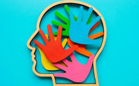 Bunte Hände im Kopfprofil symbolisieren die Vielfalt der Wahrnehmung. Wer stellt Autismus fest? Fachleute mit Verständnis für diese neurologische Besonderheit.
