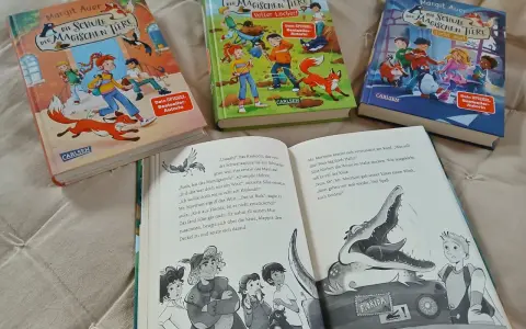 Drei Bücher der Reihe "Die Schule der magischen Tiere" von Margit Auer liegen nebeneinander. Aufgeschlagen ist ein Band mit einem Krokodil und einem Jungen.