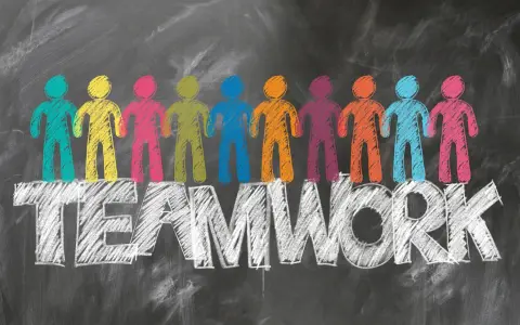Bunte Figuren stehen auf dem Wort TEAMWORK. Tolle Ideen für die Klassenlehrerstunde, die Zusammenarbeit fördern.