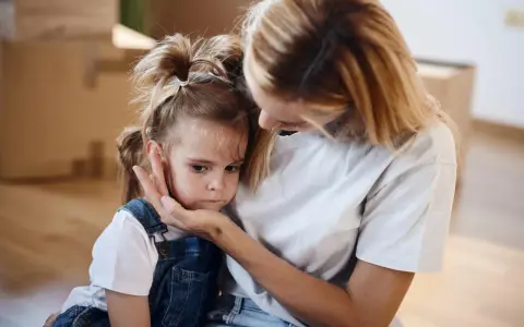 Mutter tröstet ihr Kind, das Angst vor anderen Kindern hat.