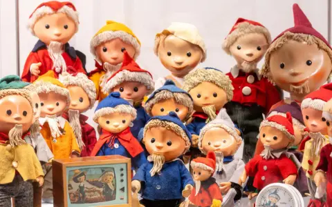 Eine Sammlung von Sandmann-Charakteren in bunten Kostümen, einige mit Bart und Mützen, stehen dicht gedrängt.