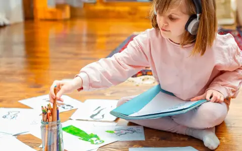Mädchen mit Kopfhörern wählt Buntstift für Zeichnung. Kreativer Umgang mit Asperger-Kindern durch Kunst.