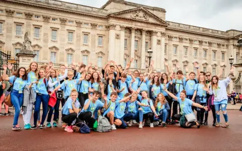 Eine fröhliche Gruppe Jugendlicher vor dem Buckingham Palace, bereit für ihr sprachcamp englisch.