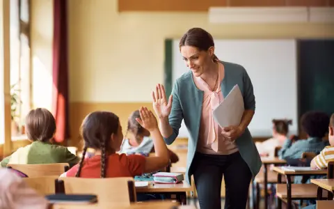 Lehrerin gibt einem Grundschüler einen High-Five. So kann man Kinder zum Lernen motivieren.