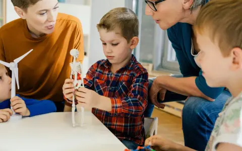 Kinder lernen mit einem Skelettmodell und einem Windrad. Die Lehrerin erklärt geduldig, wie wichtig es ist, sich auf Details zu konzentrieren, auch bei ads adhs.