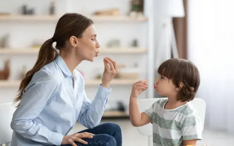 Eine Frau und ein Kind machen Lippenbewegungen. Dies kann ein Hinweis sein, um autismus erkennen kind.