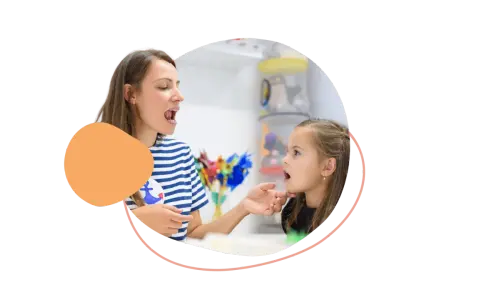 Logopädin zeigt einem Mädchen, wie man Laute richtig formt. So lernen Kinder am besten neue Sprechfähigkeiten.