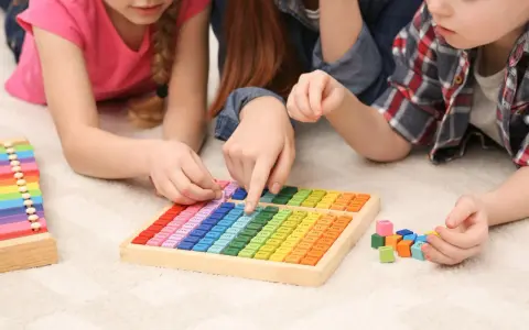 Kinder lernen spielerisch Mathe mit bunten Holzbausteinen und einem kleinen Abakus.
