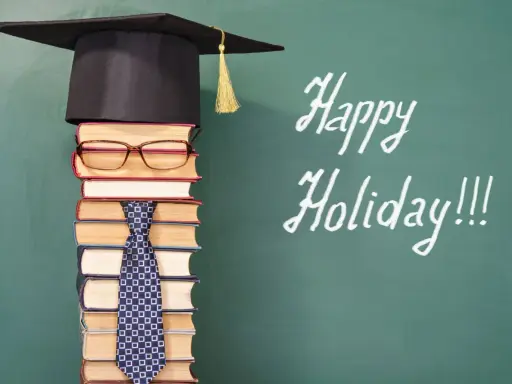 Ein Stapel Bücher mit Hut und Krawatte, der an die letzte Schulwoche erinnert. "Happy Holiday!!!" steht auf der Tafel.