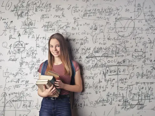 Ein lächelndes Mädchen mit Büchern vor einer Wand voller mathematischer Formeln. Sie zeigt, wie kann man sich in Mathe verbessern: durch Lernen und Üben.