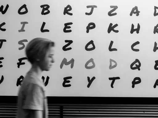 Junge vor Buchstabenwand, die LRS-Symptome in der 2. Klasse verdeutlichen könnte.