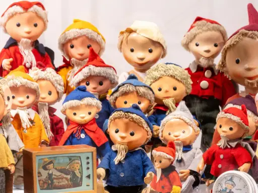 Eine Sammlung von Sandmann-Charakteren in bunten Kostümen, einige mit Bart und Mützen, stehen dicht gedrängt.