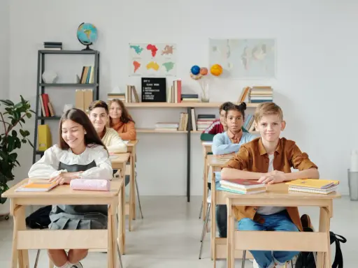 Schüler sitzen an Holztischen. Eine Lehrerin könnte hier kreative Sitzordnung Grundschule Ideen umsetzen.