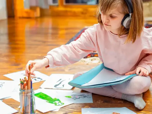 Mädchen mit Kopfhörern wählt Buntstift für Zeichnung. Kreativer Umgang mit Asperger-Kindern durch Kunst.