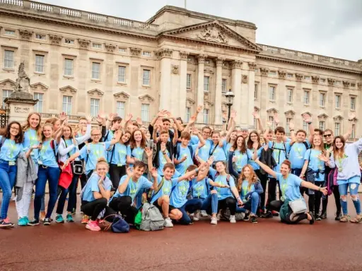 Eine fröhliche Gruppe Jugendlicher vor dem Buckingham Palace, bereit für ihr sprachcamp englisch.
