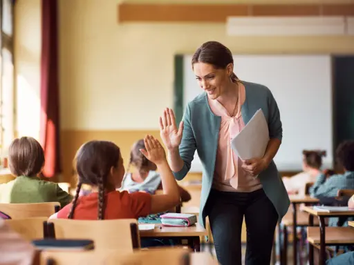 Lehrerin gibt einem Grundschüler einen High-Five. So kann man Kinder zum Lernen motivieren.