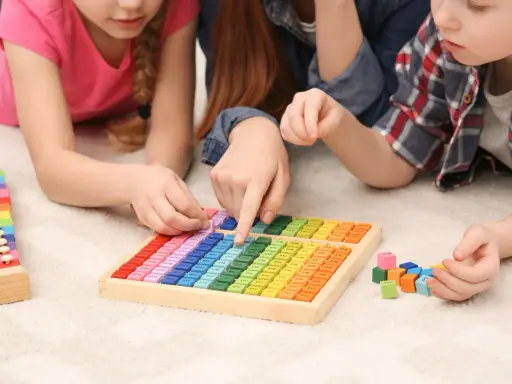 Kinder lernen spielerisch Mathe mit bunten Holzbausteinen und einem kleinen Abakus.